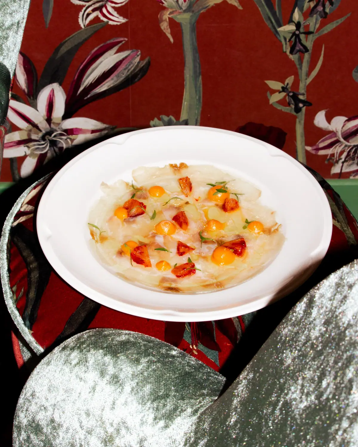Entrée fraîche de carpaccio de poisson blanc, agrémenté de physalis et herbes aromatiques.