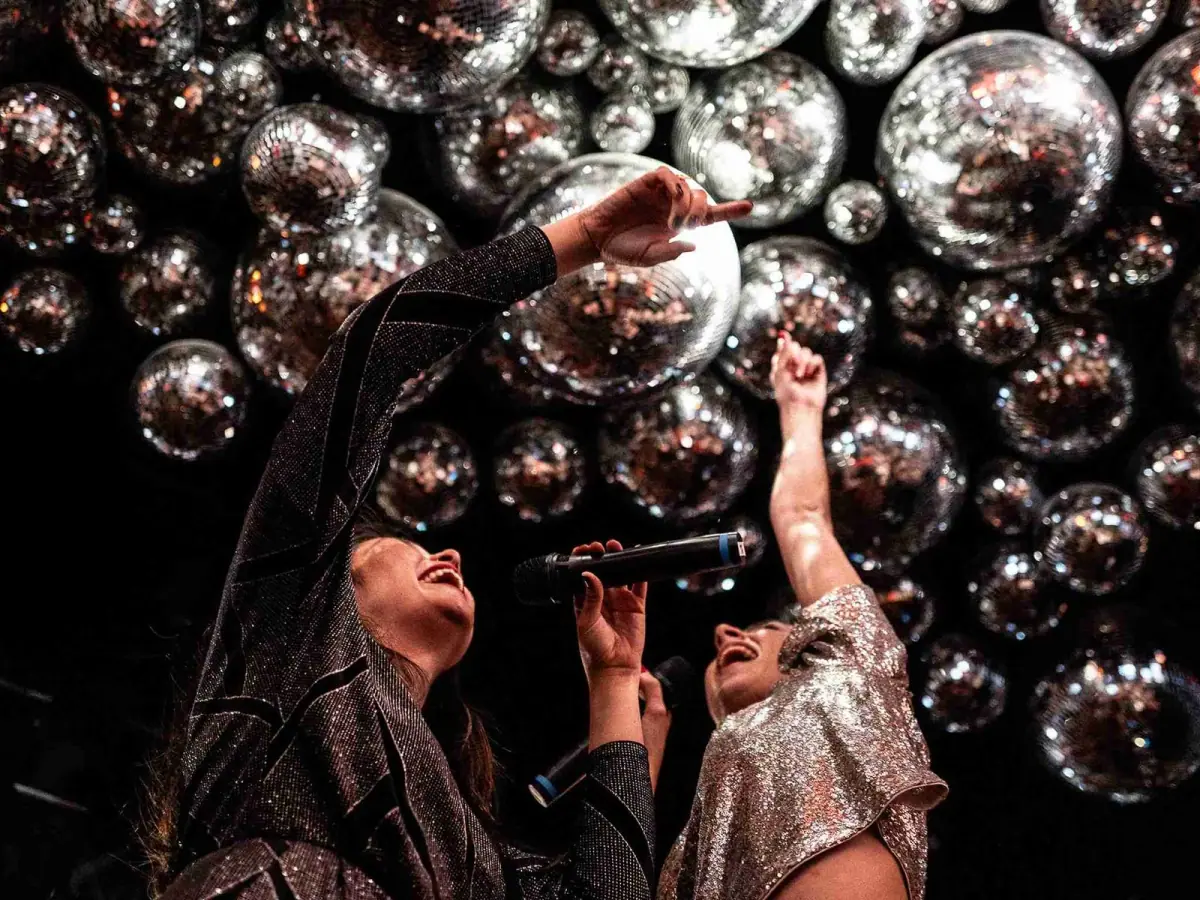 Deux amies chantent au karaoké du Nouvel An de Madame Claude, sous des dizaines de boules à facettes
