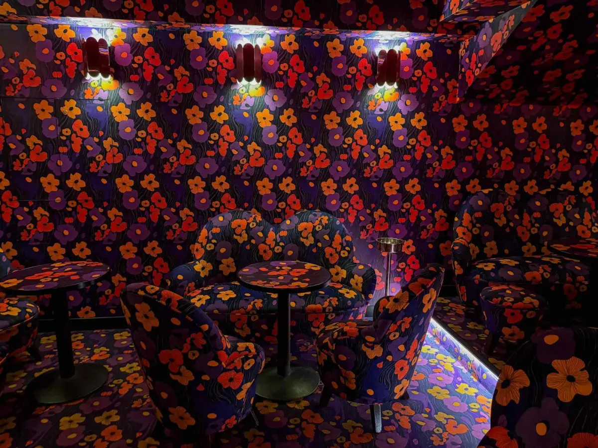Intérieur de la salle karaoké privée : papier peint floral, banquettes en velours et tables basses
